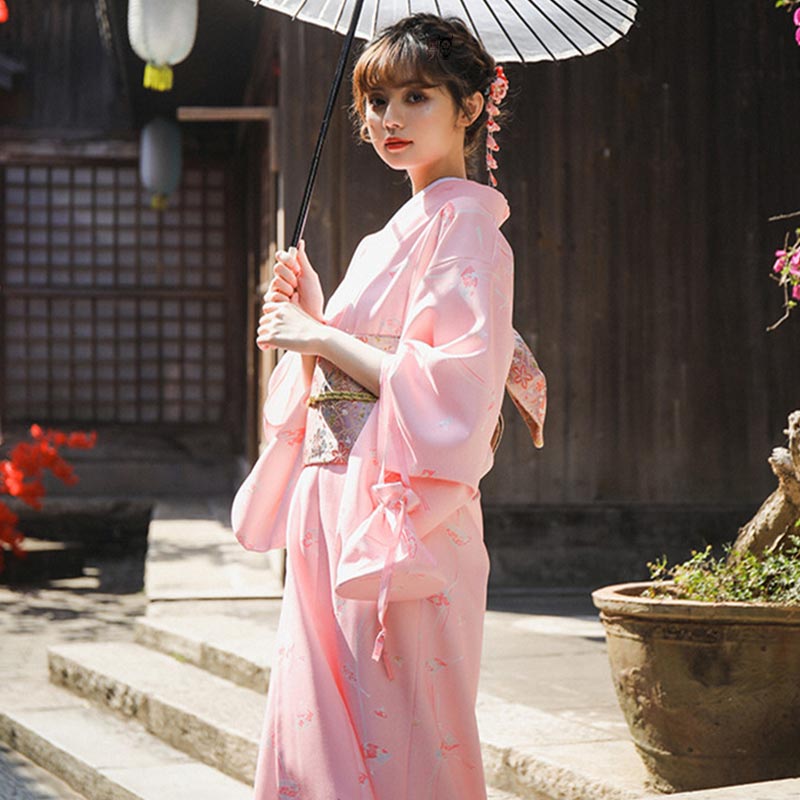 Frau im traditionellen Kimono mit Sakura Obi Gürtel, Sonnenschirm und Kanzashi-Haarschmuck