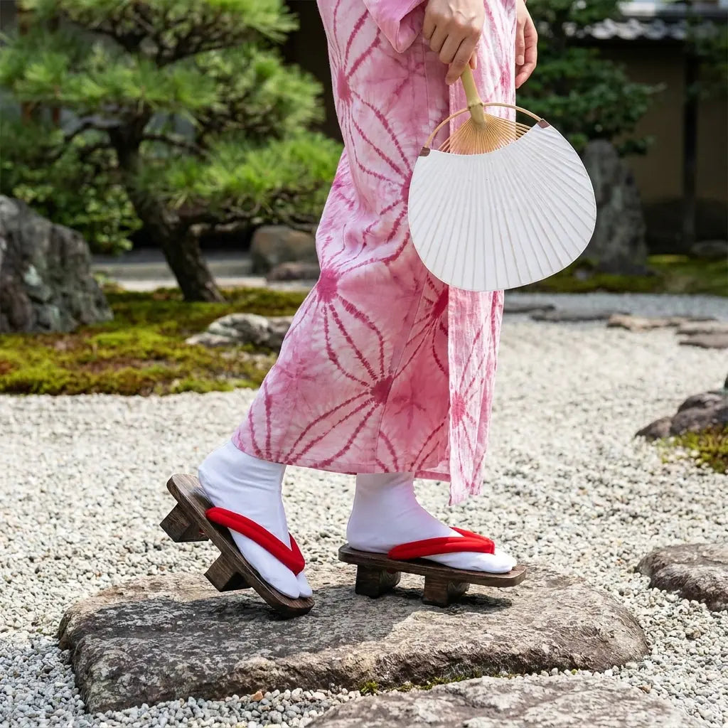 Geta Sandalen getragen mit einem rosa Kimono in einem japanischen Garten