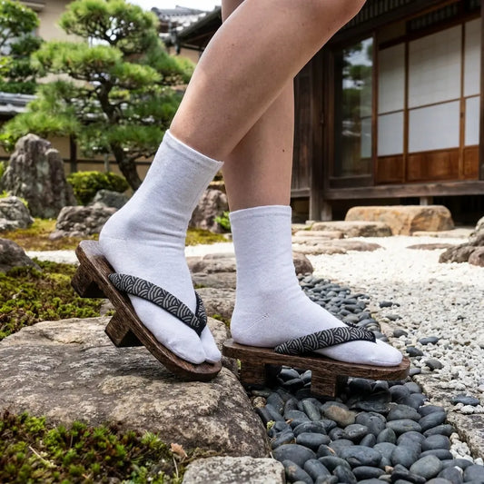 Geta Sandalen im Seigaiha-Stil mit weißen Tabi-Socken in einem japanischen Garten getragen
