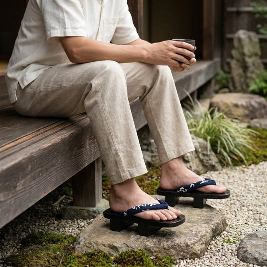 Geta Sandalen getragen mit weißen Tabi-Socken auf steinigem Gartenweg