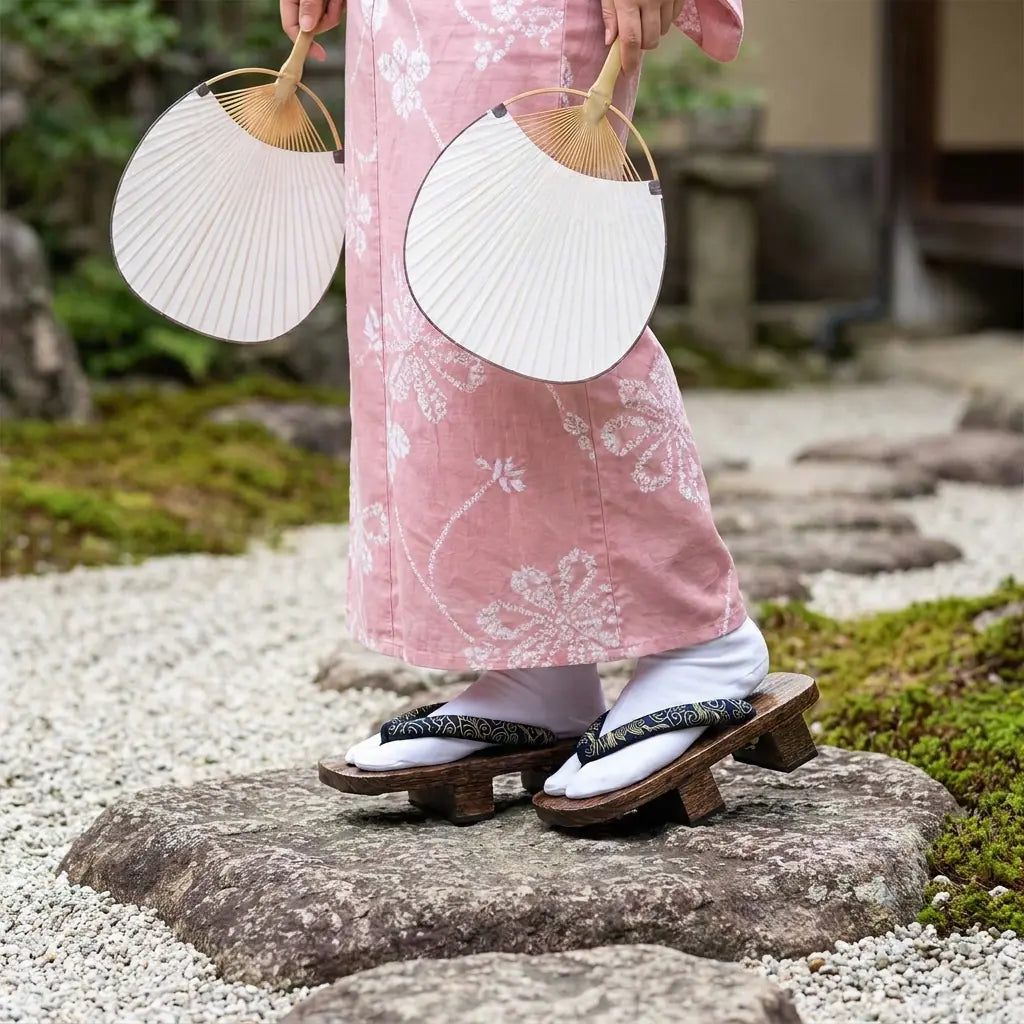 Holz-Geta-Sandalen getragen mit einem rosa Kimono im japanischen Garten