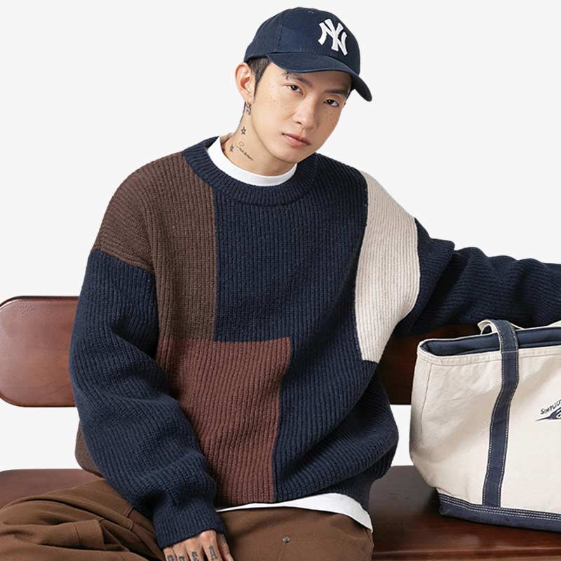 Mann sitzt auf einem Stuhl in einem Navy Oversize Pullover aus Kaschmir-Polyester-Mischung mit Hut