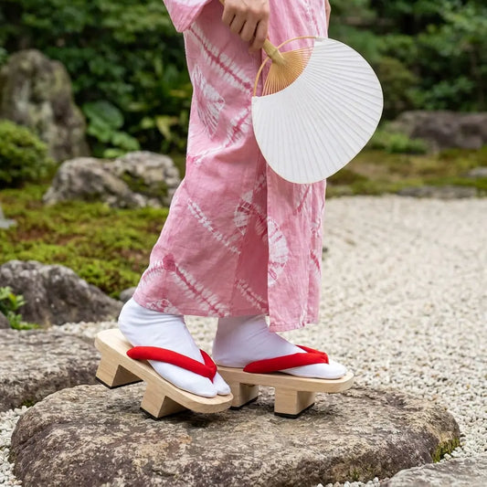 Japanische Geta Sandalen getragen mit rosa Kimono in japanischem Garten