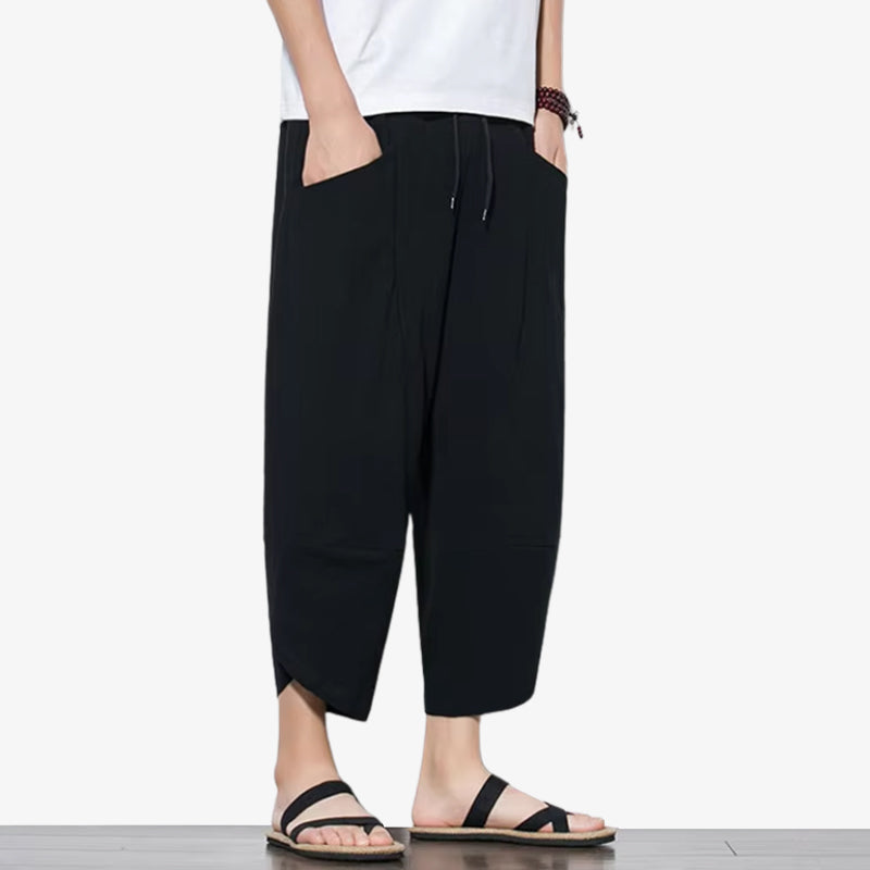 Ein Mann trägt eine schwarze japanische Hose kombiniert mit Sandalen und einem weißen T-Shirt.