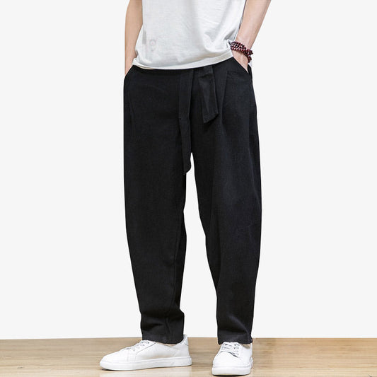 Mann trägt weite schwarze japanische Hose mit Obi Gürtel und weißen Sneakers