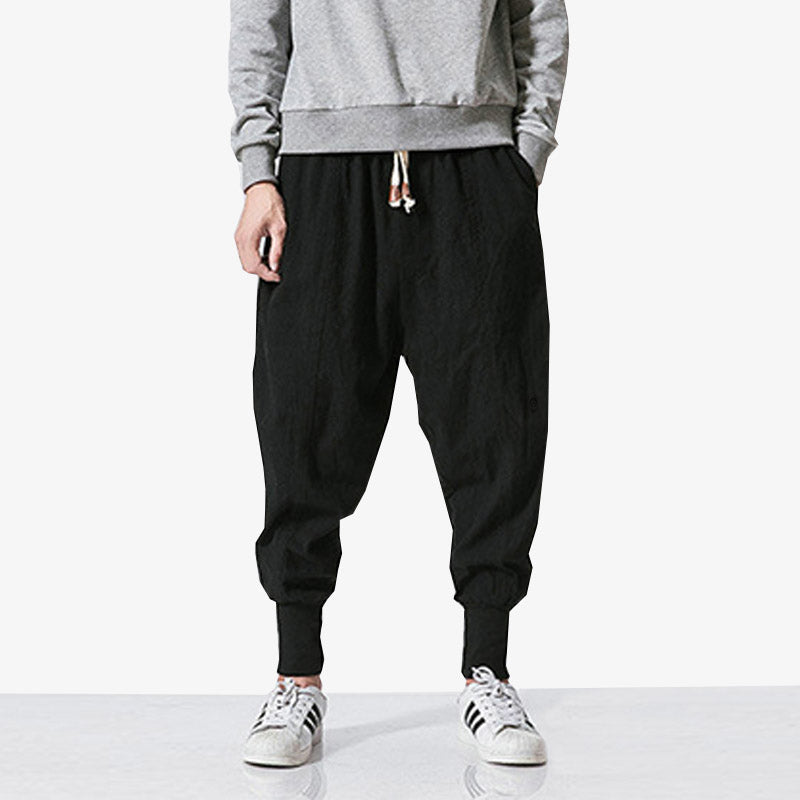 Mann trägt schwarze Streetwear Hose mit weißen Sneakers und Pullover