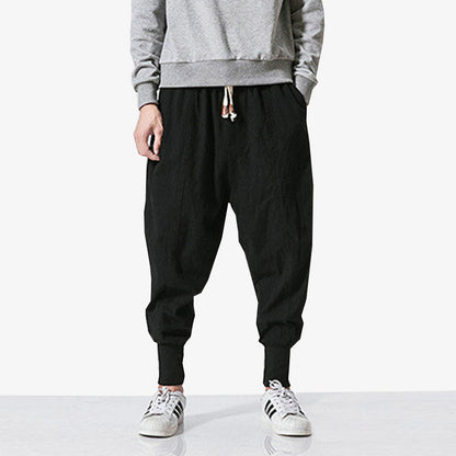 Mann trägt schwarze Streetwear Hose mit weißen Sneakers und Pullover