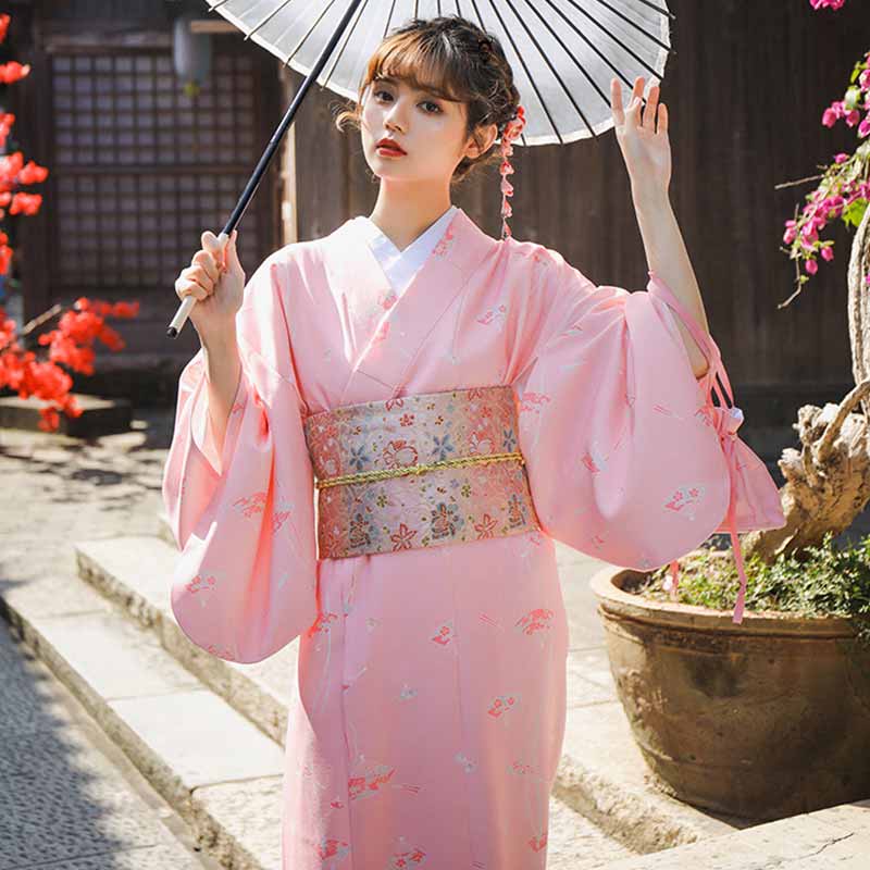 Frau im Kimono trägt einen Sakura Obi Gürtel mit floralem Stickmuster und Sonnenschirm