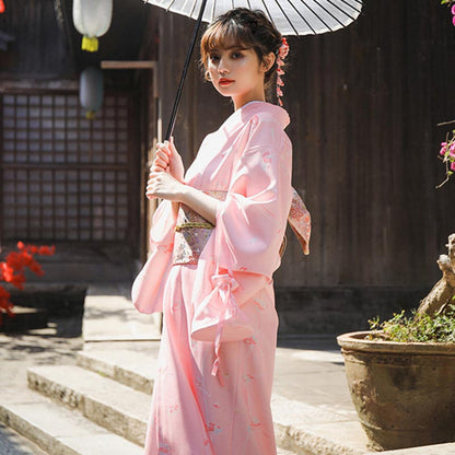 Frau im traditionellen Kimono mit Sakura Obi Gürtel, Sonnenschirm und Kanzashi-Haarschmuck