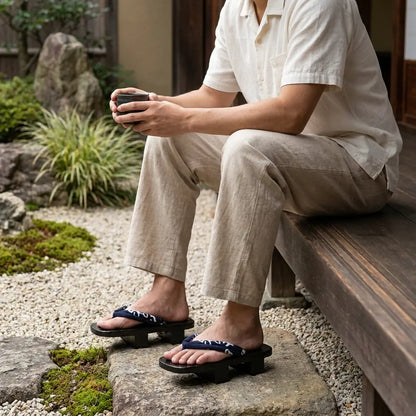 Geta Sandalen Herren mit weißen Tabi-Socken auf einem Gartenweg aus Stein