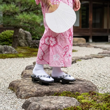 Geta Sandalen aus Holz getragen mit einem rosa Kimono im japanischen Garten