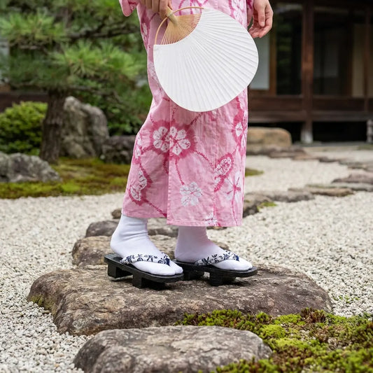 Geta Sandalen aus Holz getragen mit einem rosa Kimono im japanischen Garten