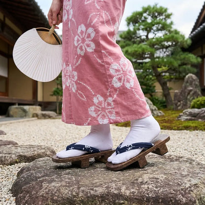 Geta Sandalen getragen mit einem rosa Kimono im japanischen Garten