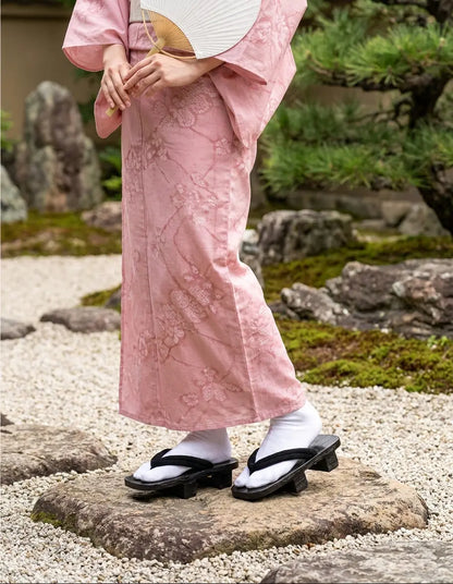 Geta Sandalen getragen mit einem rosa Kimono in einem japanischen Garten