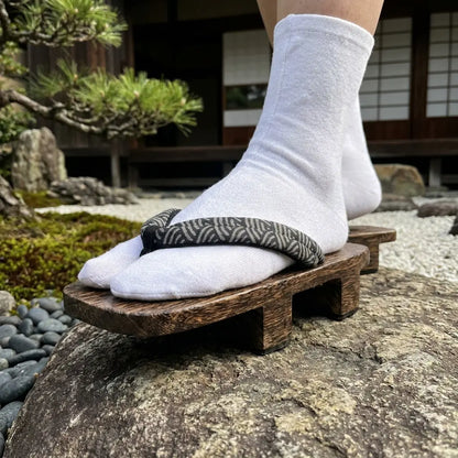 Geta Sandalen im Seigaiha-Stil auf einem Stein im japanischen Garten getragen
