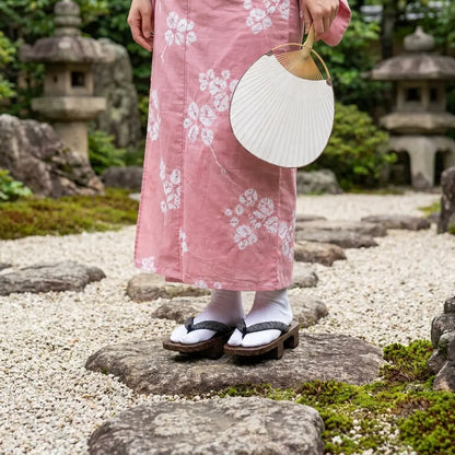 Geta Sandalen im Seigaiha-Stil mit einem rosa Kimono im Garten getragen