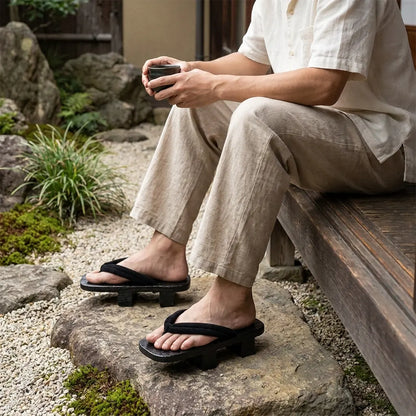 Mann sitzt erneut im japanischen Garten und trägt Geta Sandalen mit weißen Tabi-Socken