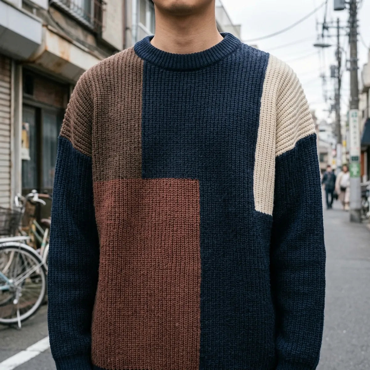 Nahaufnahme des gerippten Rundhalsausschnitts und der groben Strickstruktur in Navy und Schokoladenbraun