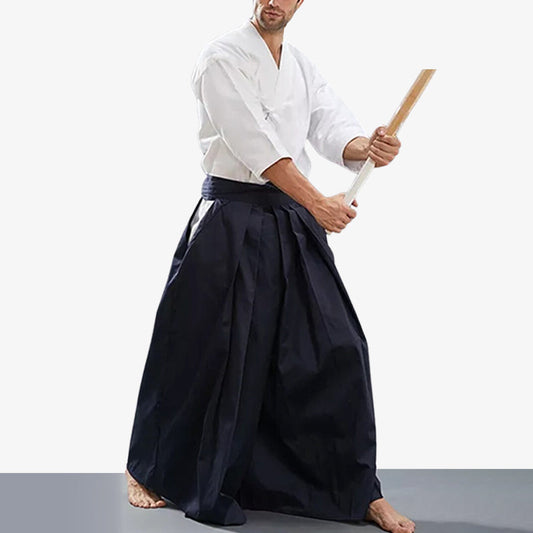 Kampfkünstler trägt blaue Hakama Hose mit weißem Keikogi und Holzschwert
