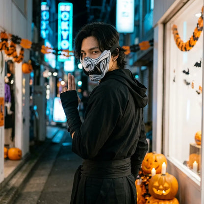 Halloween Menpo Maske kombiniert mit schwarzem Ninja-Outfit in leerer Straße
