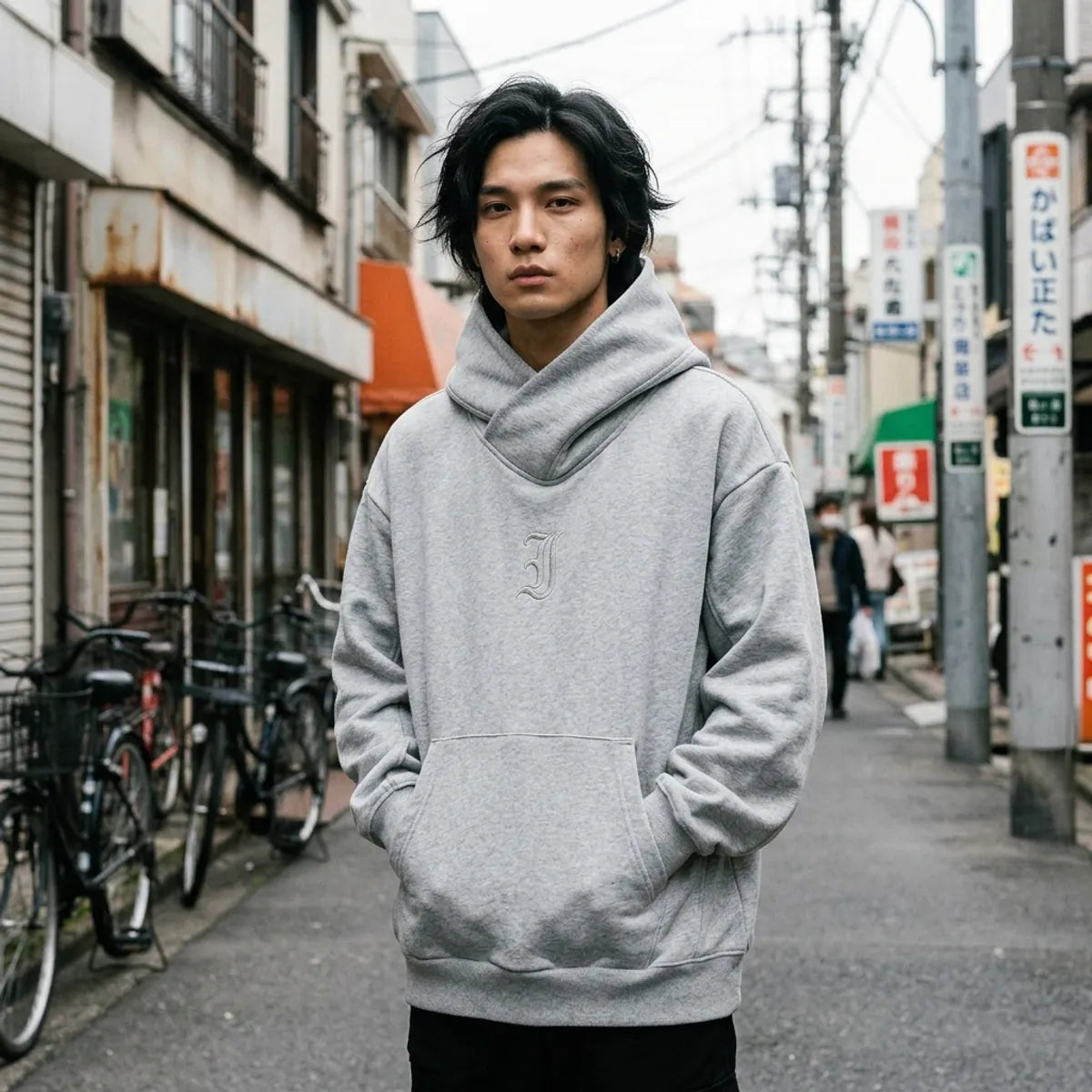 Grauer Harajuku Hoodie mit gekreuztem Trichterkragen, oversized getragen mit Händen in der Kängurutasche