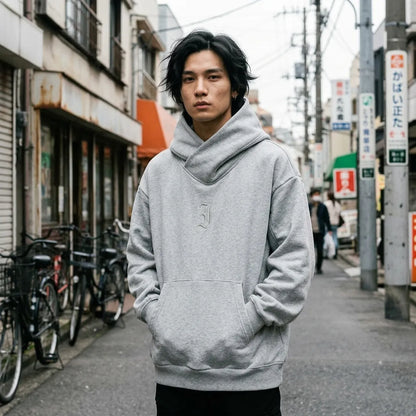 Grauer Harajuku Hoodie mit gekreuztem Trichterkragen, oversized getragen mit Händen in der Kängurutasche