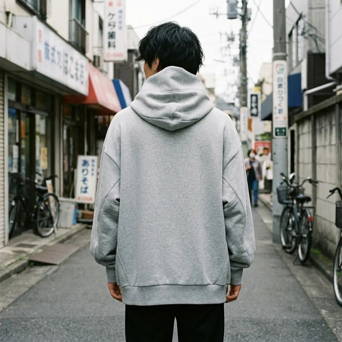 Rückansicht des grauen Oversized Hoodies mit hoher Trichterkapuze hinter dem Kopf