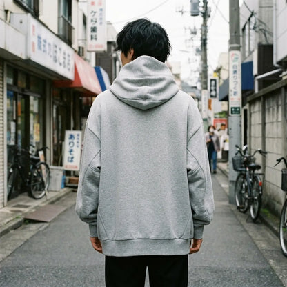 Rückansicht des grauen Oversized Hoodies mit hoher Trichterkapuze hinter dem Kopf