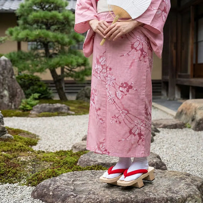Japanische Geta Sandalen getragen mit rosa Kimono in japanischem Garten