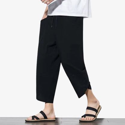 Ein Mann trägt eine schwarze japanische Hose mit lockerer Passform und dezenten Details.