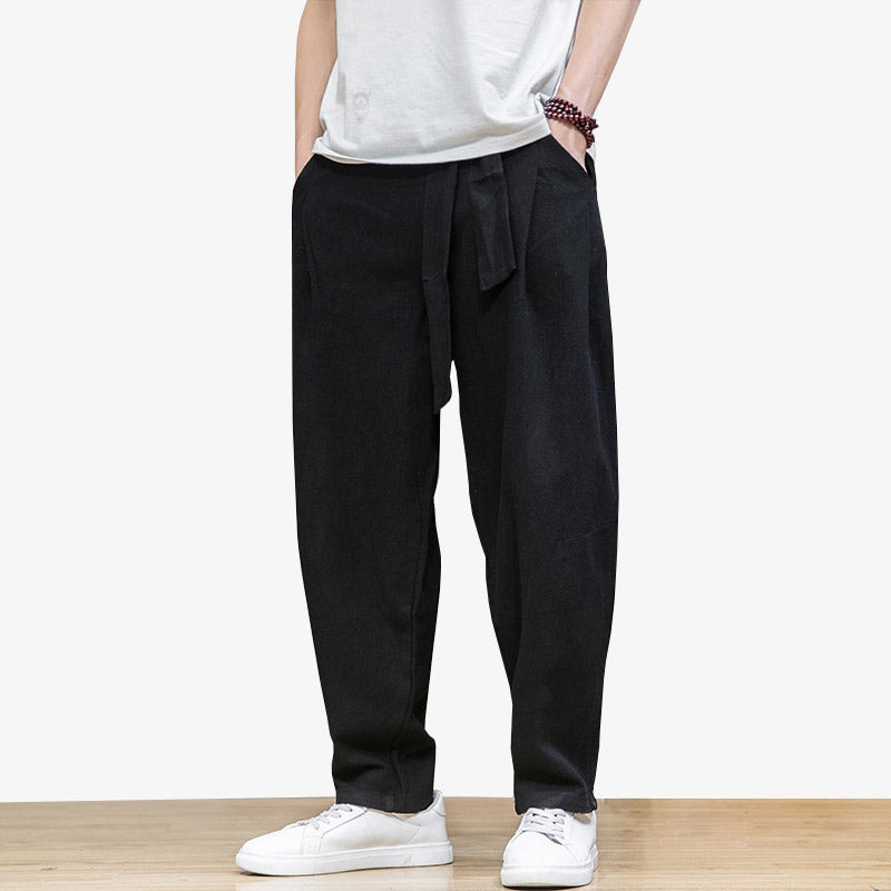 Mann trägt weite schwarze japanische Hose mit Obi Gürtel und weißen Sneakers