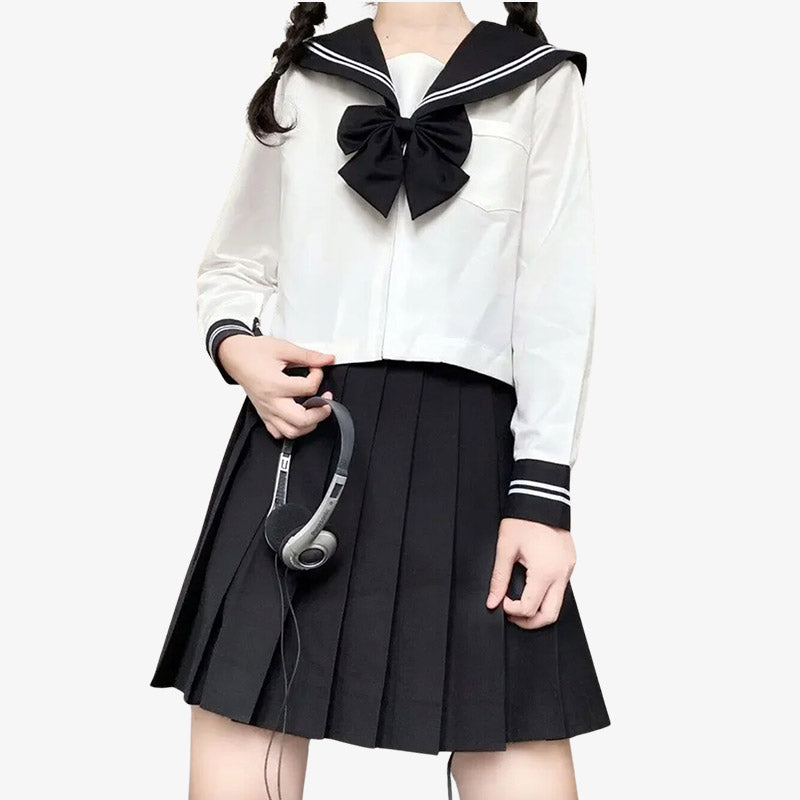 Frau steht in japanischer Schulmädchen-Matrosenuniform mit schwarzem Rock, weißer Bluse und gestreifter Schleife