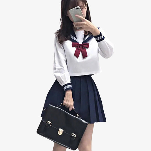 Frau trägt japanische Schuluniform mit blauem Rock, weißer Bluse und schwarzer Schultasche
