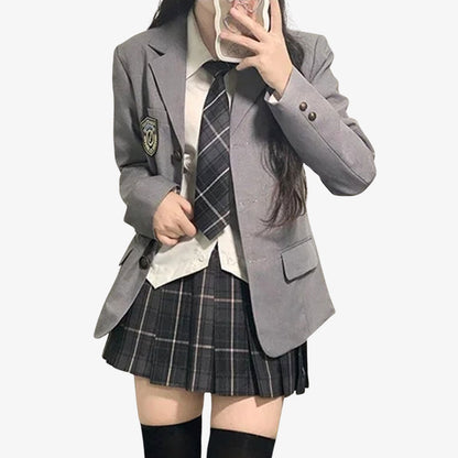 Frau im grauen Blazer mit kariertem Rock, weißem Hemd und Krawatte für Cosplay