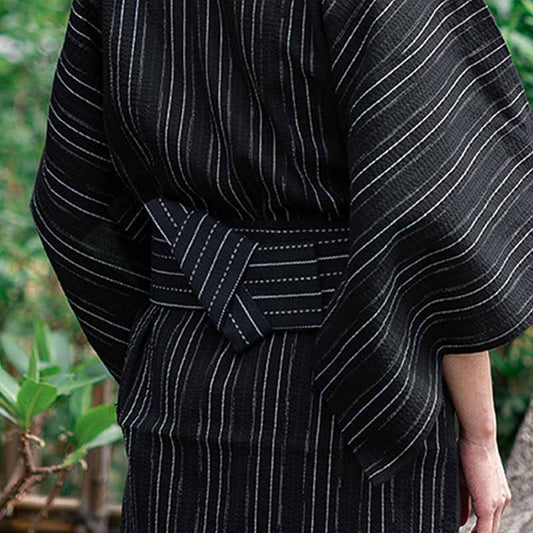 Mann bindet Baumwoll Kimono mit japanischem Obi Gürtel in Schwarz