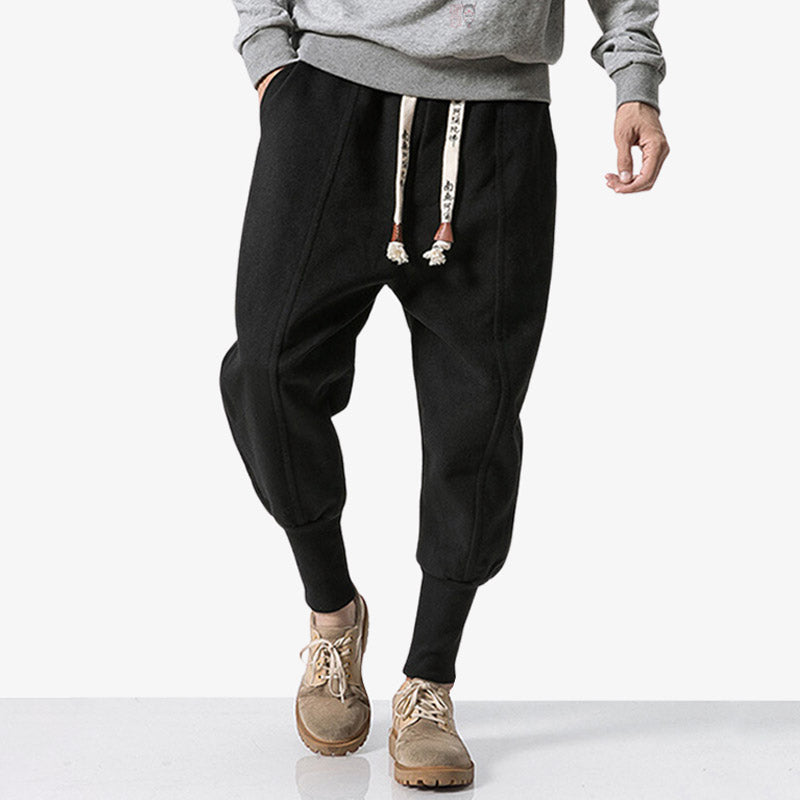 Mann trägt schwarze Nikka Hose mit Kanji bedrucktem Kordelzug im Streetwear-Stil