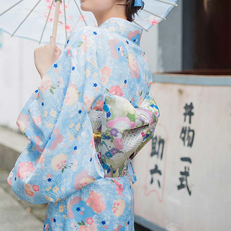 Frau in einer Straße trägt Obi Gürtel über einem geblümten Kimono-Kleid