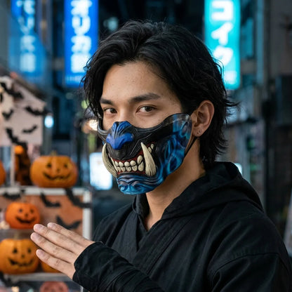 Schwarz-blaue Oni Halbmaske mit weißen Reißzähnen bei Halloween, blaues Neonlicht im Hintergrund