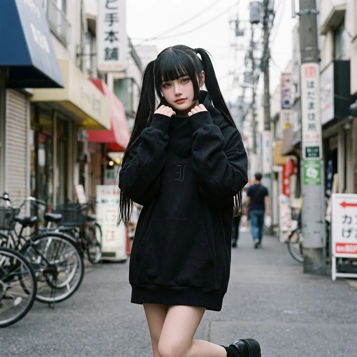 Schwarzer Oversized-Hoodie, getragen von einer Frau in Harajuku, der Trichterkragen eng um den Hals gewickelt