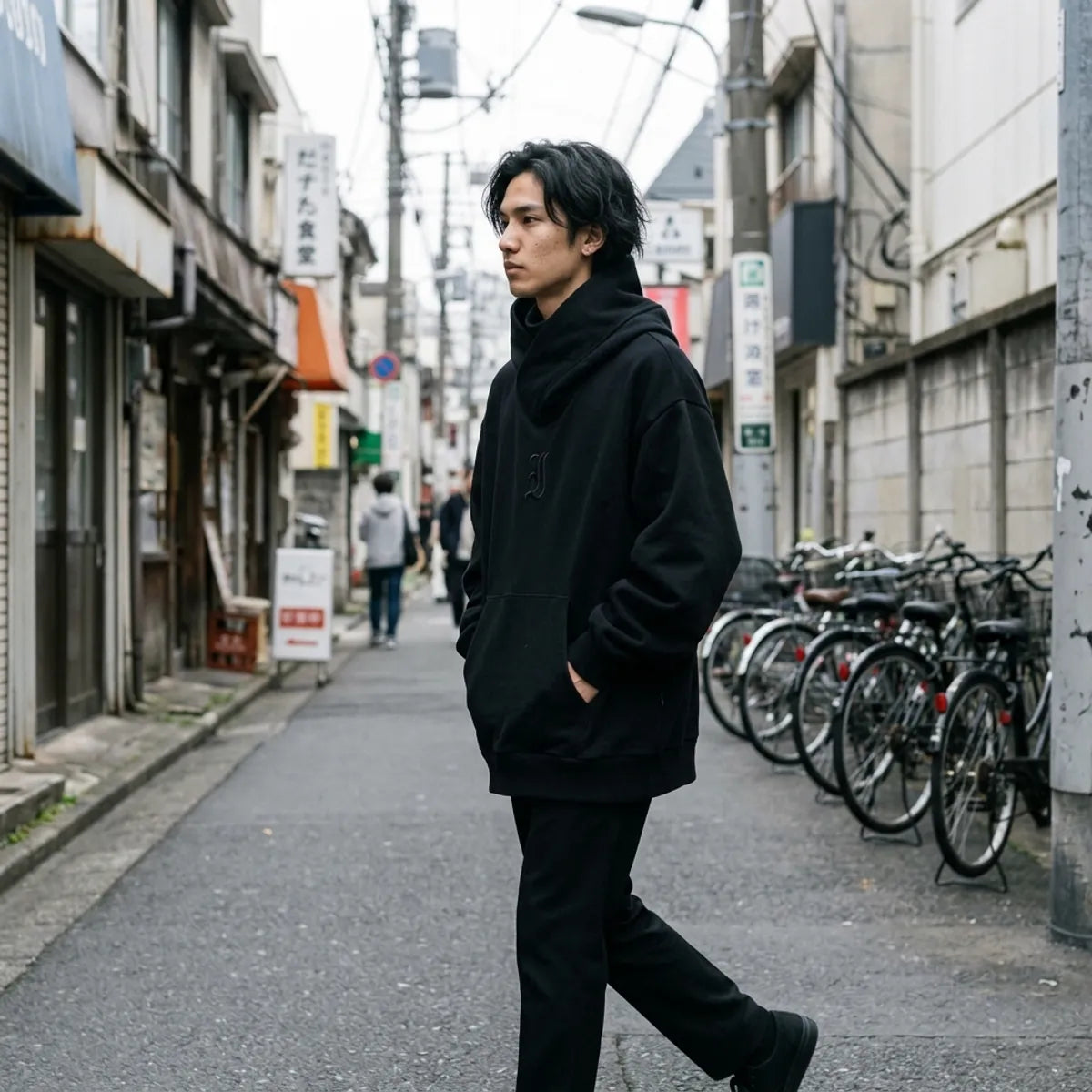 Schwarzer Oversized-Hoodie für Herren mit fallenden Schultern und weiten Ärmeln beim Gehen in Harajuku
