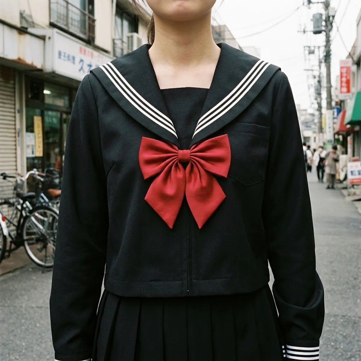 Nahaufnahme des schwarzen Sailor-Kragens mit weißen Streifen und roter Satinschleife