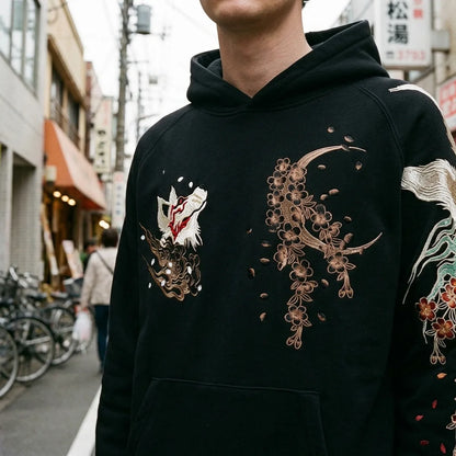 Nahaufnahme von bronzenem Halbmond und Kirschblüten auf der Brust des Hoodies bestickt