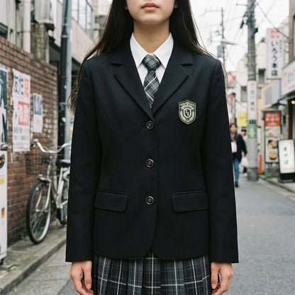 Nahaufnahme des schwarzen Schuluniform-Blazers mit gesticktem Wappen und karierter Krawatte
