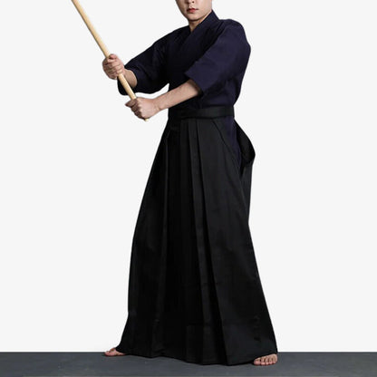 Kampfkünstler in schwarzer Hakama Hose hält ein Holzschwert in der Hand