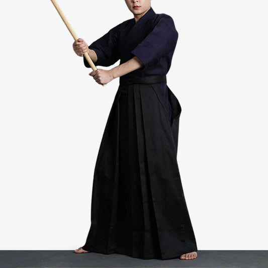 Kampfkünstler in schwarzer Hakama Hose hält ein Holzschwert in der Hand