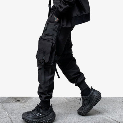 Mann trägt schwarze Techwear Hose mit mehreren Taschen und Sneakers