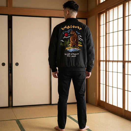 Person trägt schwarze Bomberjacke mit Bärenmotiv in einem Raum mit Tatami-Matten und Schiebetüren