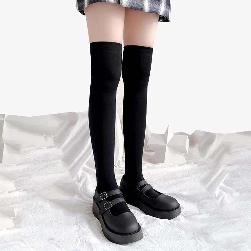 Frau trägt lange Tabi Socken zur Schuluniform mit kariertem Rock